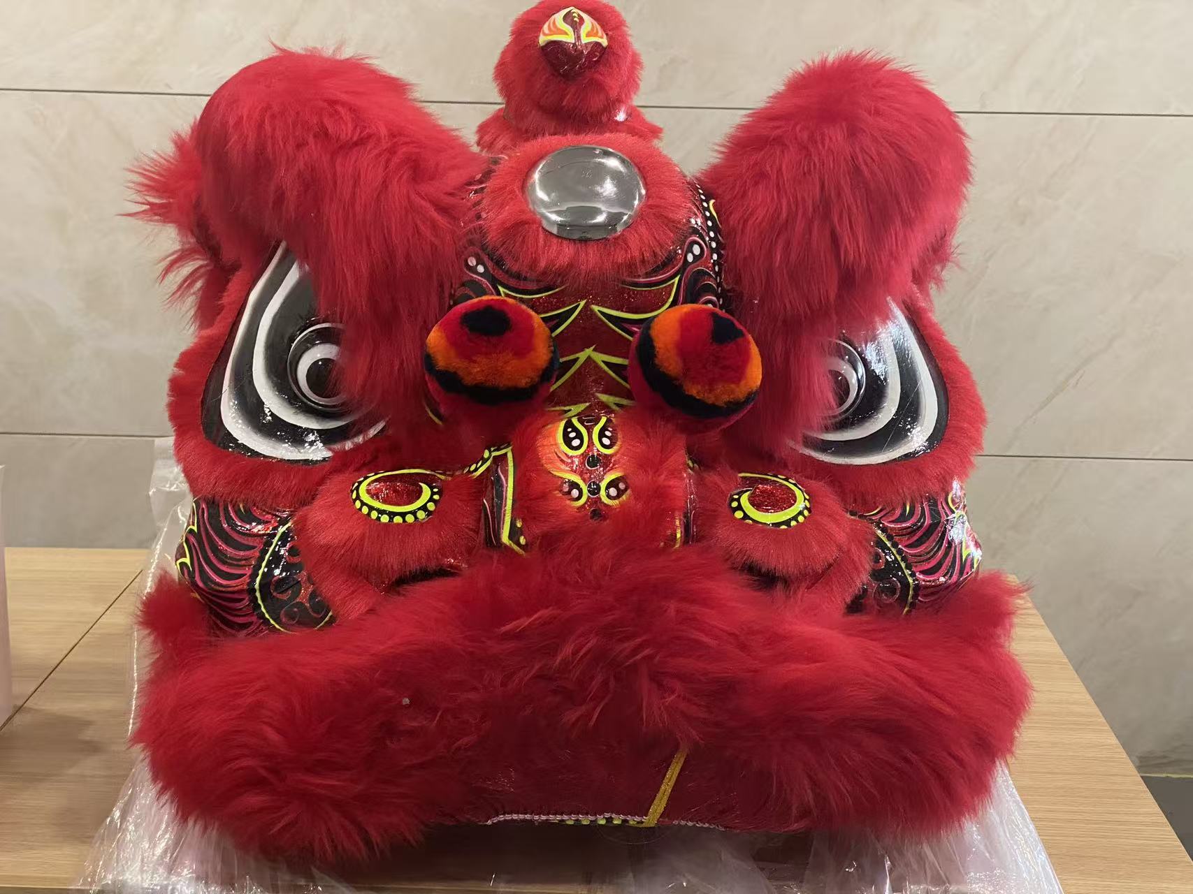 红色传统醒狮狮头，毛绒狮耳、圆眼和彩绘纹样充满生动细节